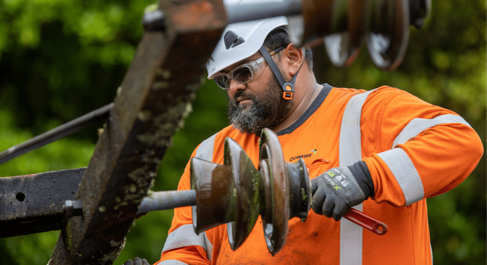 Downer crew member working on a cross-arm