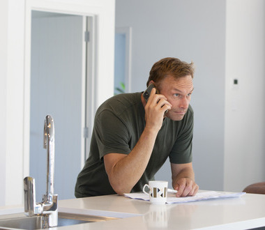 man in kitchen on phone