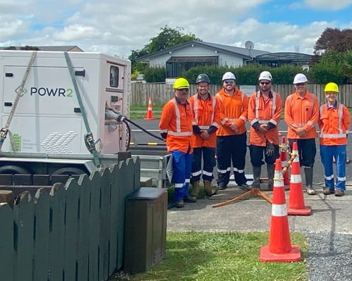 Six people in high-vis standing next to a large white container on a trailer 