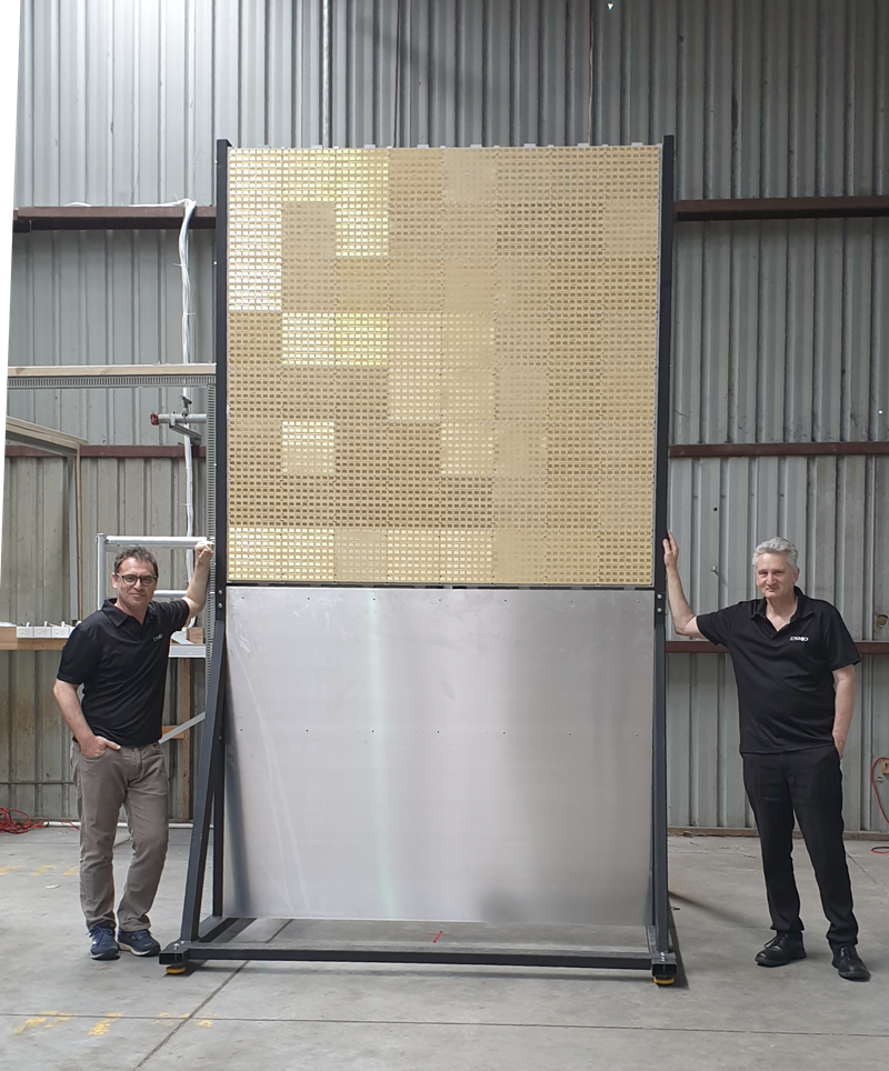 Members of the Emrod team standing next to their wireless power transmission prototype