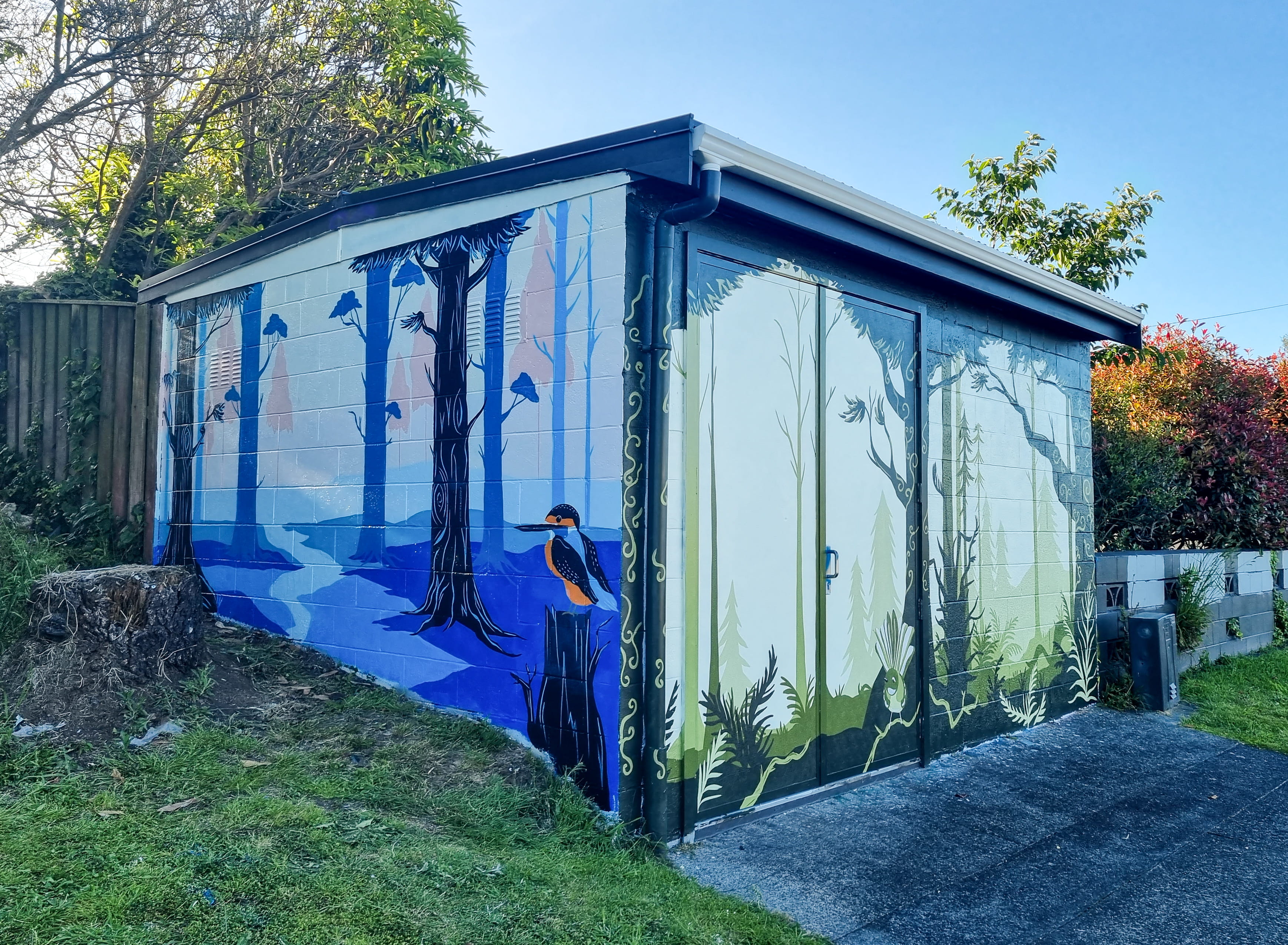 Two sides of a building featuring a mural of a forest scene with a bird.