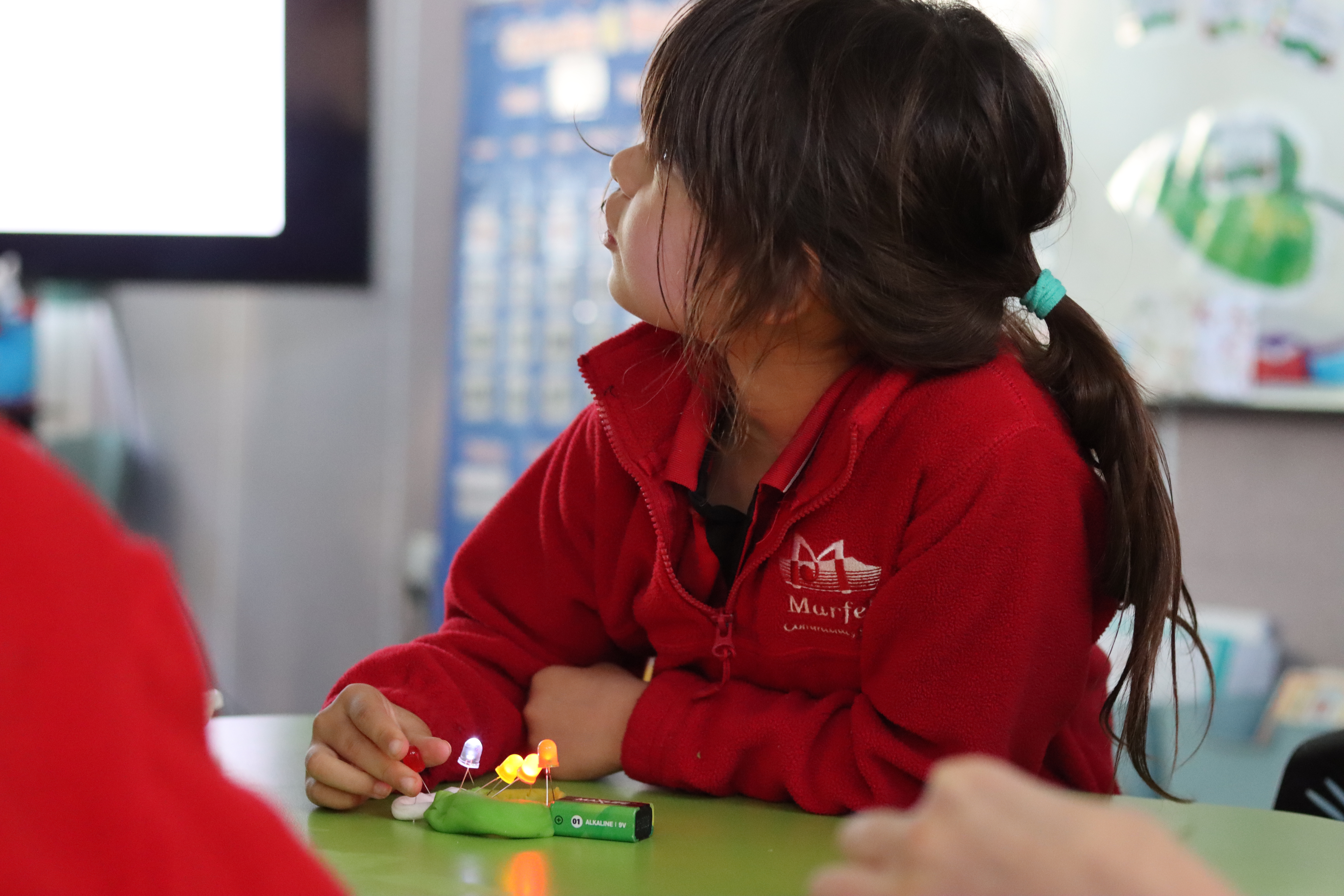 Student listening to instructions as she builds a simple electricity circuit