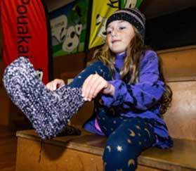 Young girl putting on knitted sock