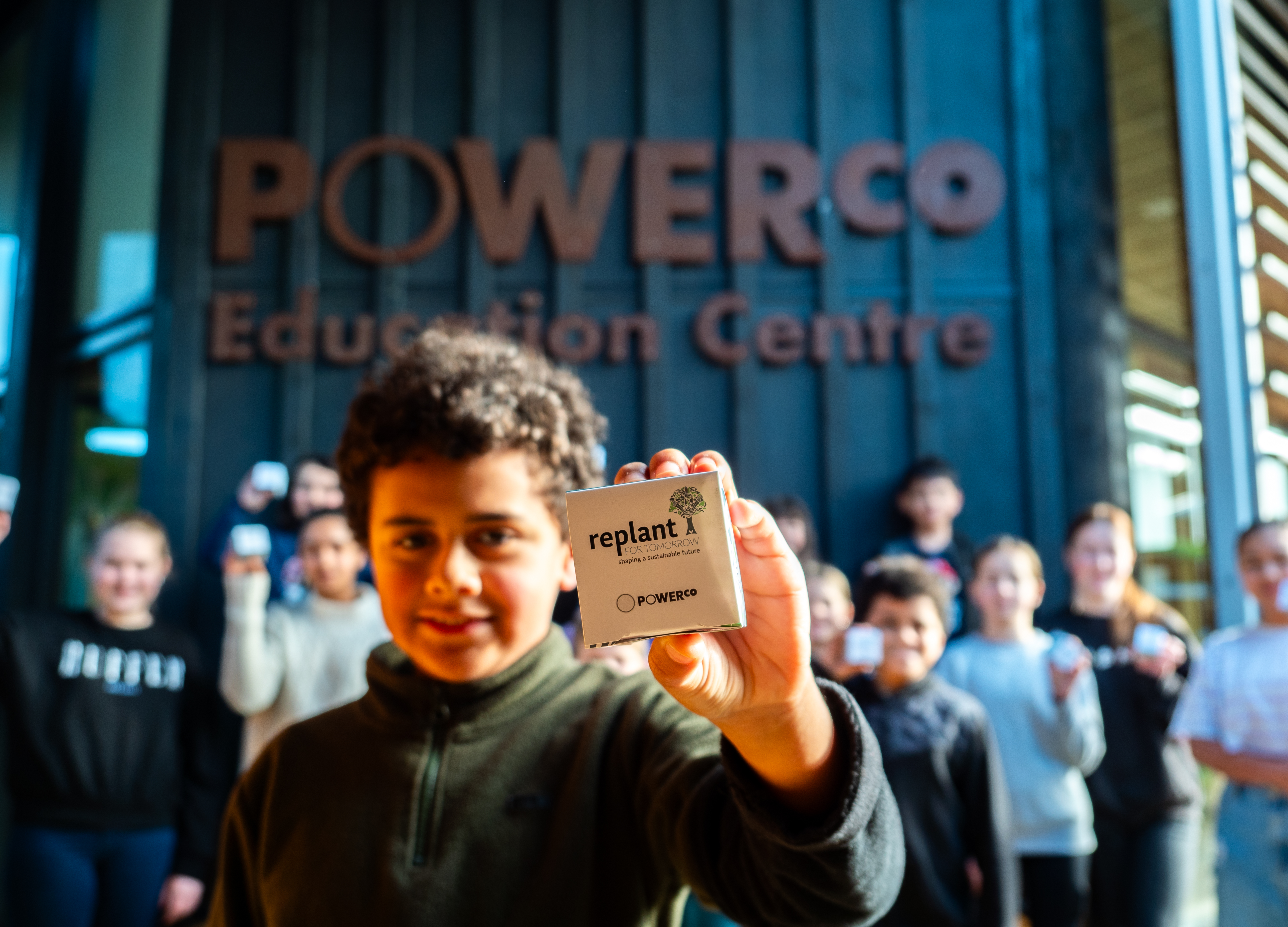 Student holding a Replant for Tomorrow seed packet outside the Powerco Education Centre