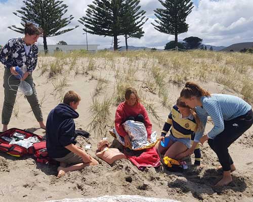 People learning CPR on beach
