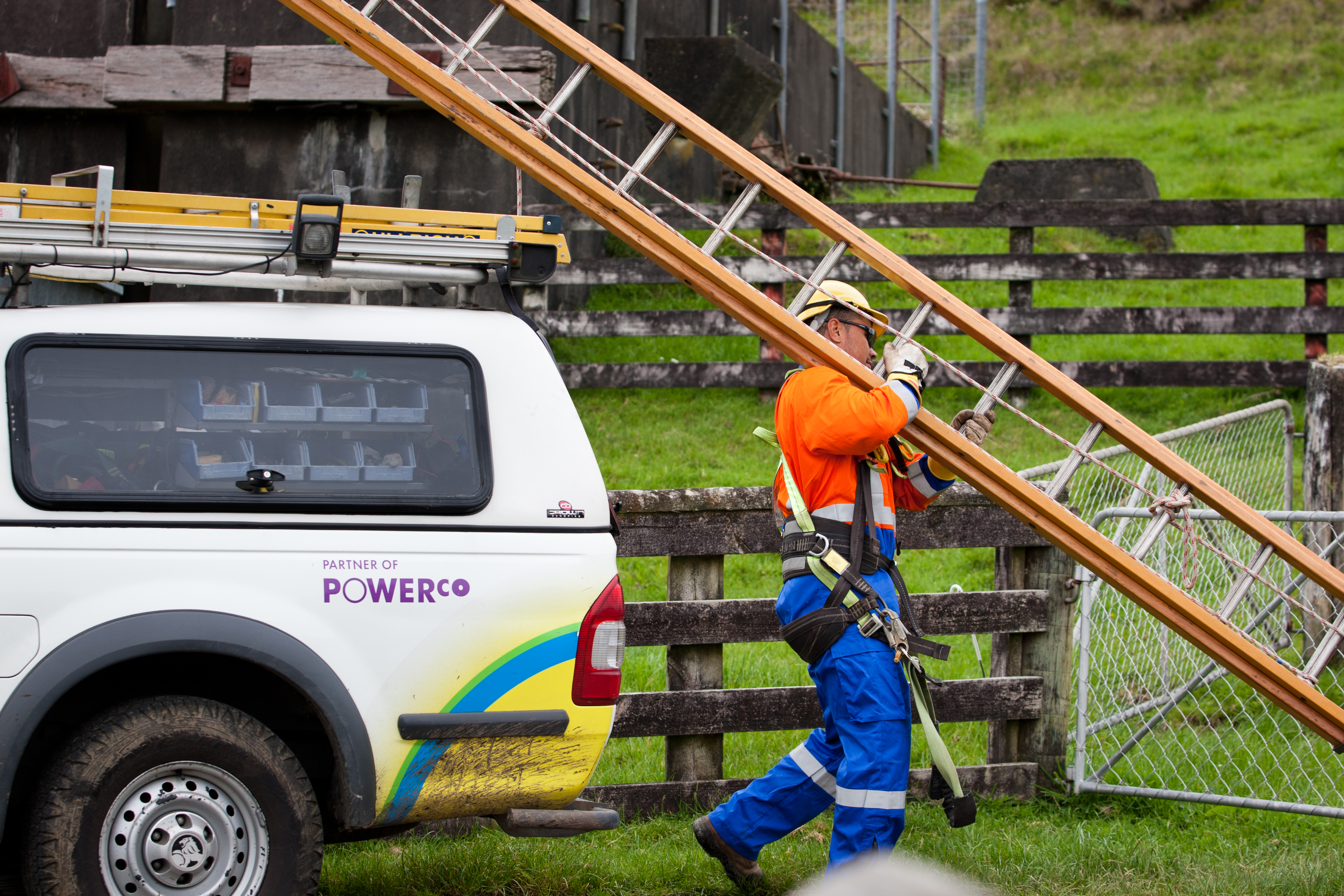 Crew member in Personal Protective Equipment carrying a ladder.