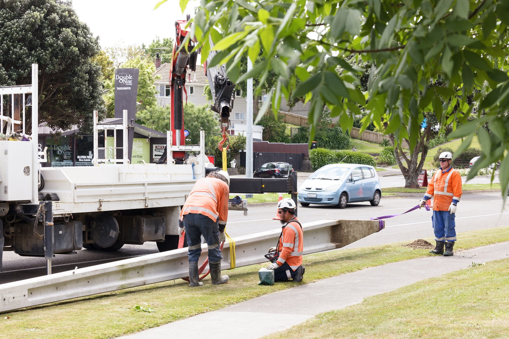 Workers in PPE on the side of the road with a power pole that is lying on the ground.