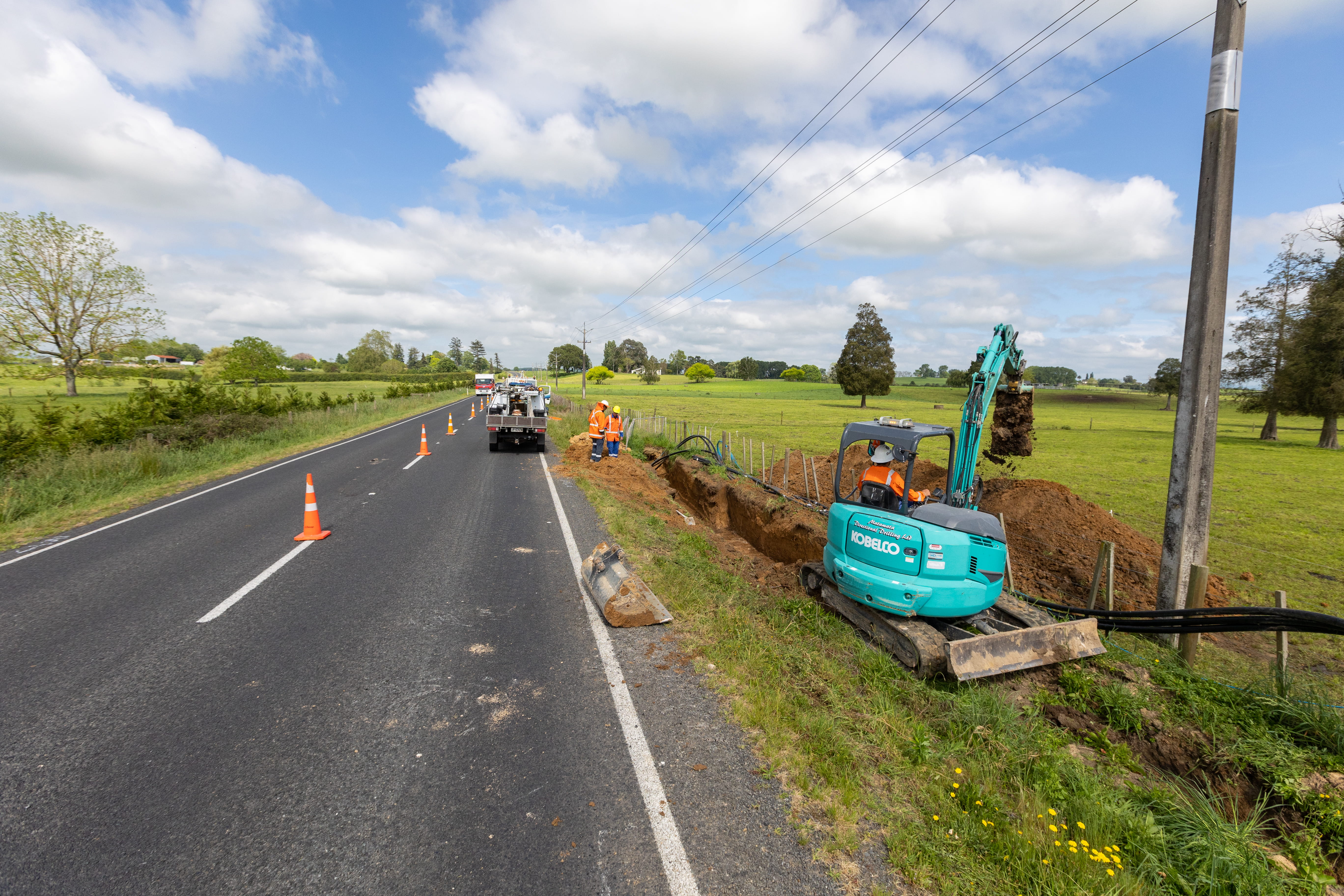 A digger digging a trench on the side of Walton Road in South Waikato