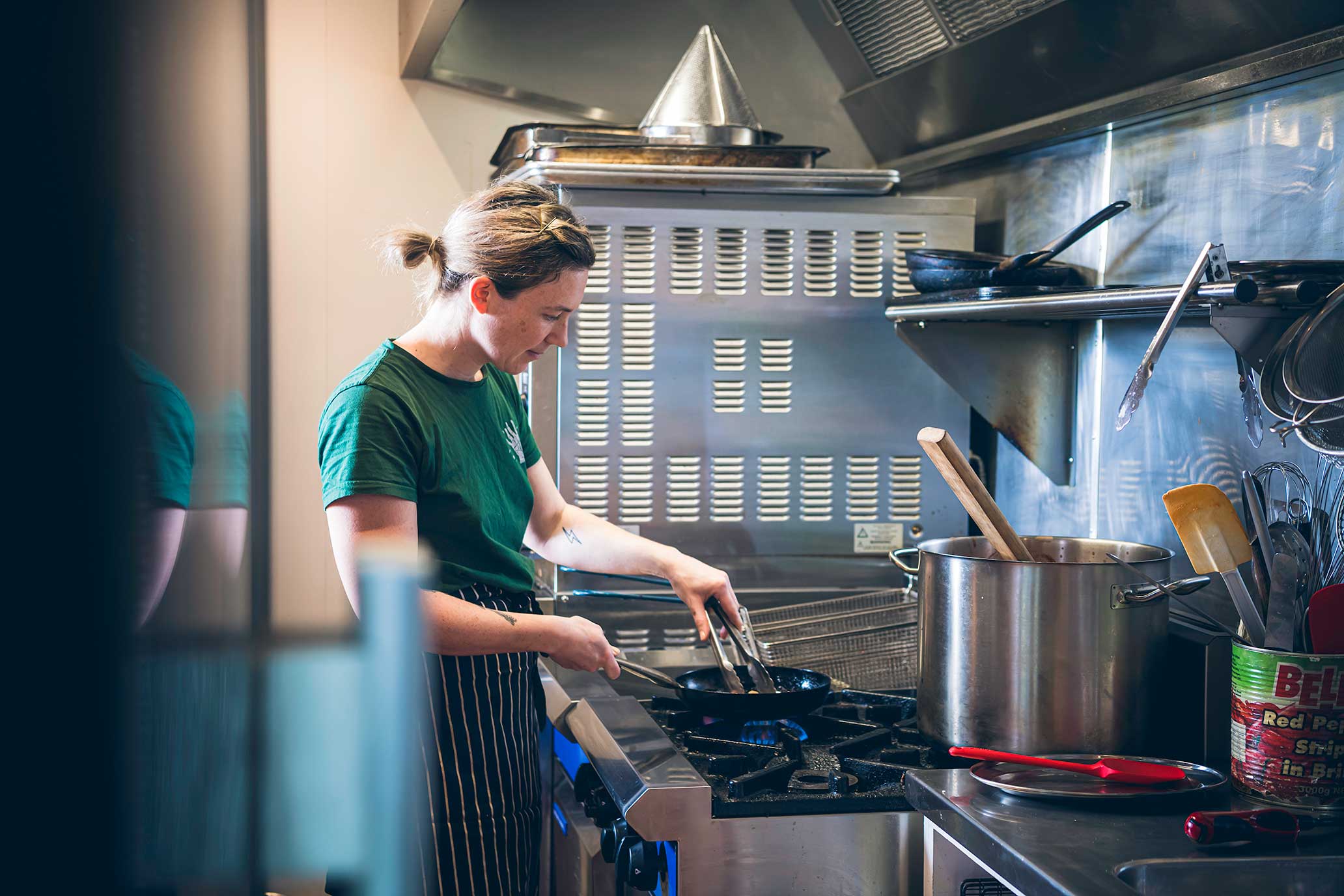 woman cooking on gas stove in commercial kitchen